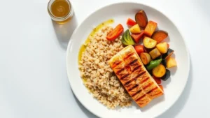 Overhead view of a balanced meal plate with grilled salmon fillet, quinoa, roasted vegetables, and olive oil drizzle on white ceramic plate, bright natural lighting, healthy food photography